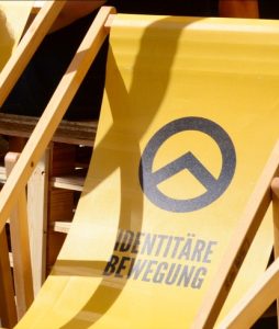 Gelbe Beach-Stuhl Lehne mit aufgedrucktem Logo und Name der Identitären Bewegung