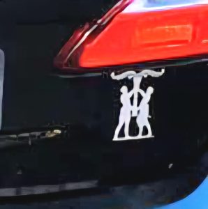 silberner Aufkleber auf einem schwarzen Autoheck, der einen Mann und eine Frau zeigt, die eine Weltenesche/Irminsul halten.